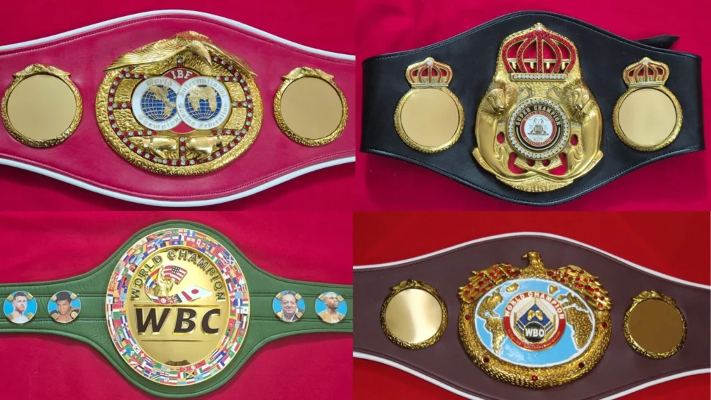 Four replica boxing championship belts in WBA, WBC, IBF and WBO style laid side by side