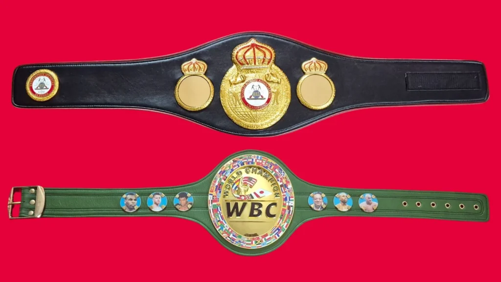 WBA style black and gold belt next to a green WBC style belt under the same light